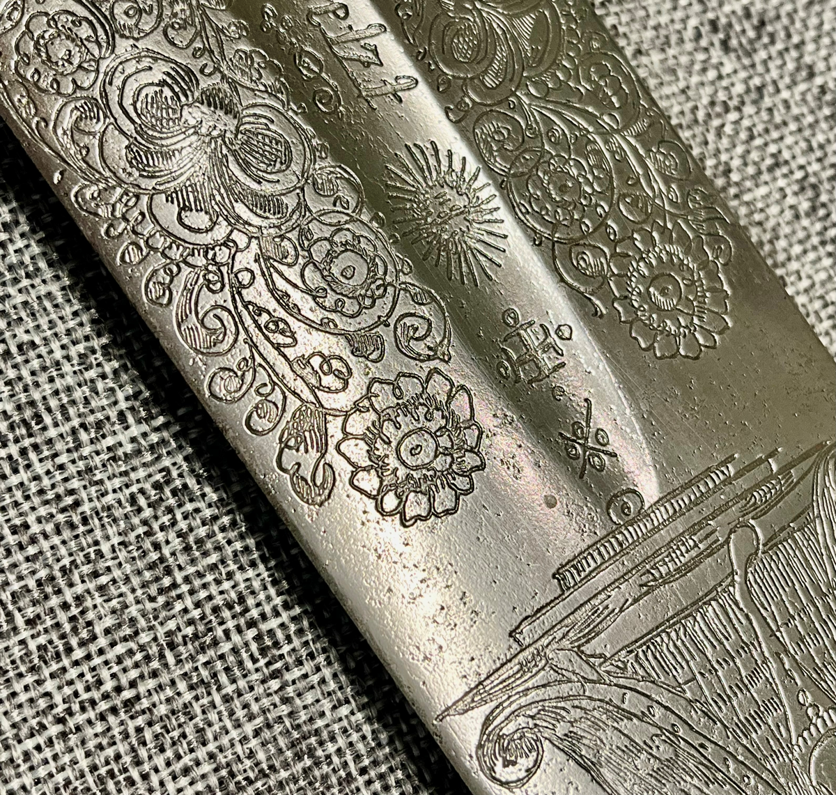 Langt tveegget sverd i stål med rett, butt klinge med kort blodrand på hver side. Klingen er rikt utsmykket med etsinger eller inngraveringer og flere merker som kan være smedmerker, blant annet en sol med menneskeansikt. Dekorert med blomsterranker, fugle- og dyremotiver og gudinnen Justitia. Grepet har hjerteformet knapp avsluttet med en mindre knapp. Stålgrep viklet med tvunnet messingtråd og satt med messingbånd oppe og nede. Symetrisk feste med flate pilformede parerstenger som smalner inn mot midten.