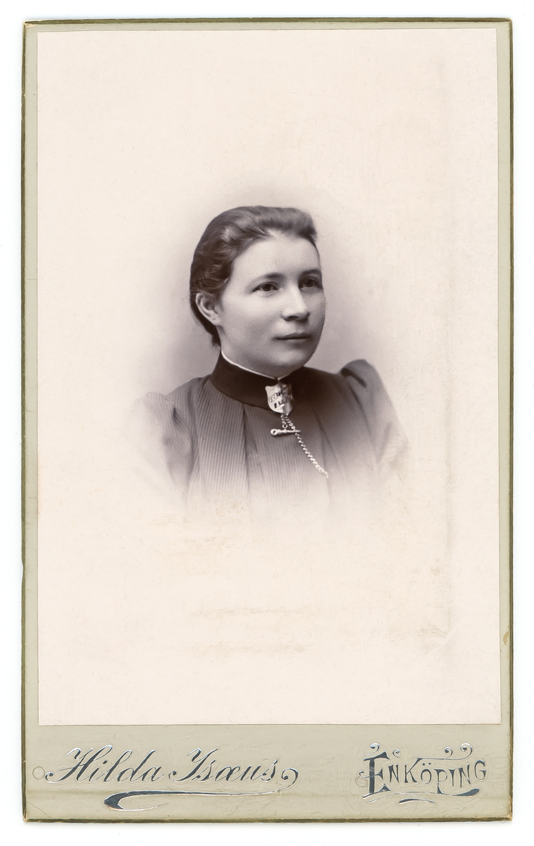 Svartvit porträtt av dam med frälsningsarméns emblem vid halsen. På baksidan står Emma Molin.