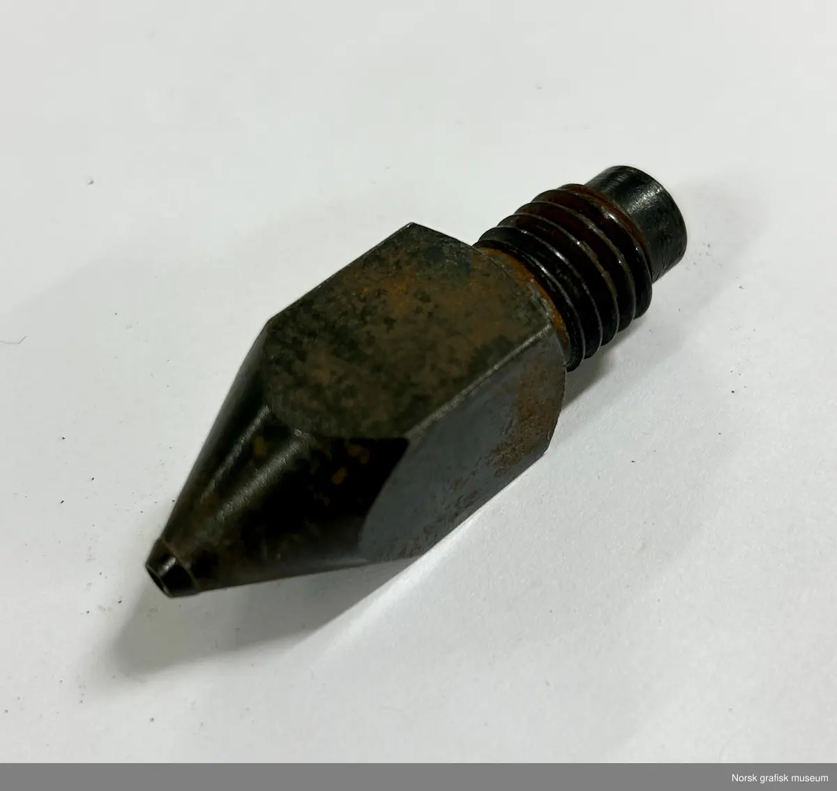 Dyse i metall med skrujenger i toppen og en konisk spiss med hull i andre enden.