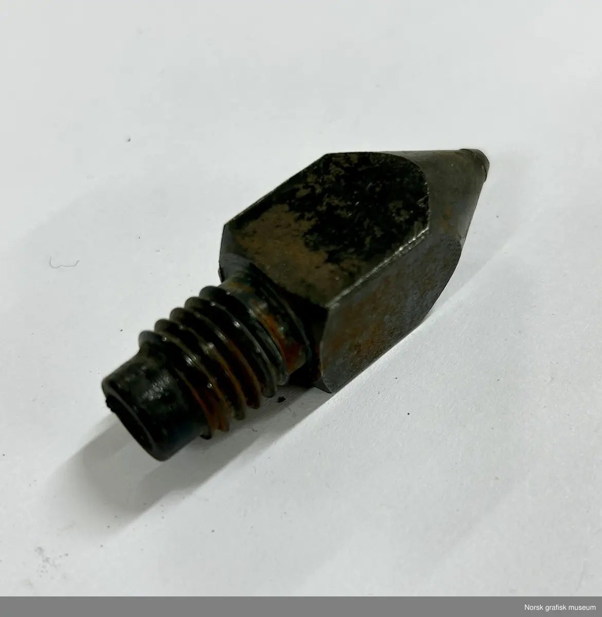 Dyse i metall med skrujenger i toppen og en konisk spiss med hull i andre enden.