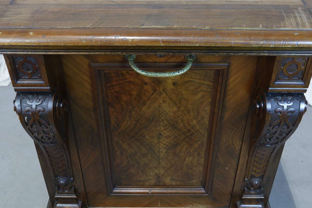 Vertikalstående, stor spilledåse av typen Polyphon, modell 54. Prod. nr. 3454. Maskinen bruker 63 cms plater.

Høyt skap i polert nøttetre med glassdør øverst og skuff nederst. Bak glassdøren ligger maskineriet og platearmen. Ved maskineriet ligger en lapp med bruksanvisning på tysk, engelsk og fransk. På skapetdøren, på hver side av glassplaten, står to rikt utskjærte dørsøyler. Øverst i hjørnene er det gjennombrudt akantus-utskjæringer. På høyre side av skapet er et myntinnkast som tar 5-øringer. Skuffen har to rikt utskjærte stolper og ornamentert metallhåndtak. Den åpnes på skrå og har plass til en rekke plater. Øverst i høyre hjørnet inne i skuffen er en mindre pengeskuff.

Til spilleren hører to små nøkler.