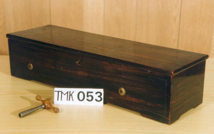 Nøkkeltrukket musikkmaskin med 12 melodier på en messingsylinder. Maskinplaten er av messing med en kam med 125 tenner. På venstre side er tre regulatorspaker. 

Kassen er lausert mørk brun på utsiden. På innsiden er den "okseblodrød" ,ed glasslokk og en skillevegg. På undersiden av lokket er det festet et melodikort. Nøkkelen ligger i en ekse i et avskilt rom på høyre side.