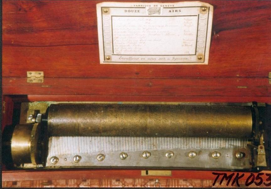 Nøkkeltrukket musikkmaskin med 12 melodier på en messingsylinder. Maskinplaten er av messing med en kam med 125 tenner. På venstre side er tre regulatorspaker. 

Kassen er lausert mørk brun på utsiden. På innsiden er den "okseblodrød" ,ed glasslokk og en skillevegg. På undersiden av lokket er det festet et melodikort. Nøkkelen ligger i en ekse i et avskilt rom på høyre side.