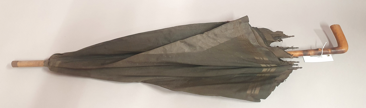 Paraply med brungrønt trekk av silke, med striper nederst. Spiler av hvalbarder og skaft av tre.