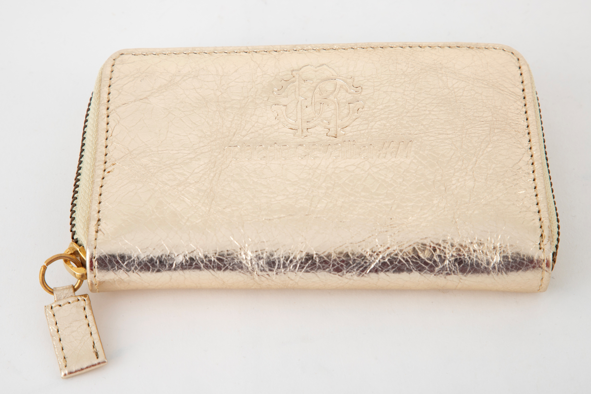 Liten veske, lukket med glidelås og med tre rom. De to hovedrommene har tre lommer hver for kort, mens skilleveggen er et lite glidelåsrom til f. eks. mynter. Innersiden er gullfarget, som yttersiden. Brukes som såkalt clutch, dvs. liten dameveske uten hank.