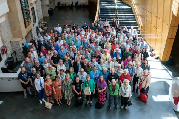 En stor gruppe mennesker fotografert innendørs fra en høyde. Alle ser opp.