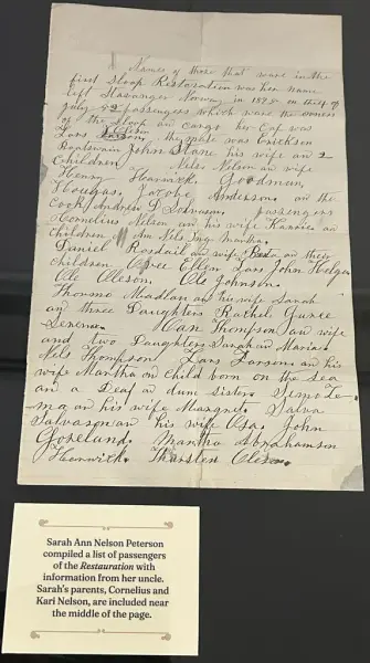 Ark med håndskrevet tekst og en trykt forklaring nedenfor til venstre. Sort bakgrunn. 