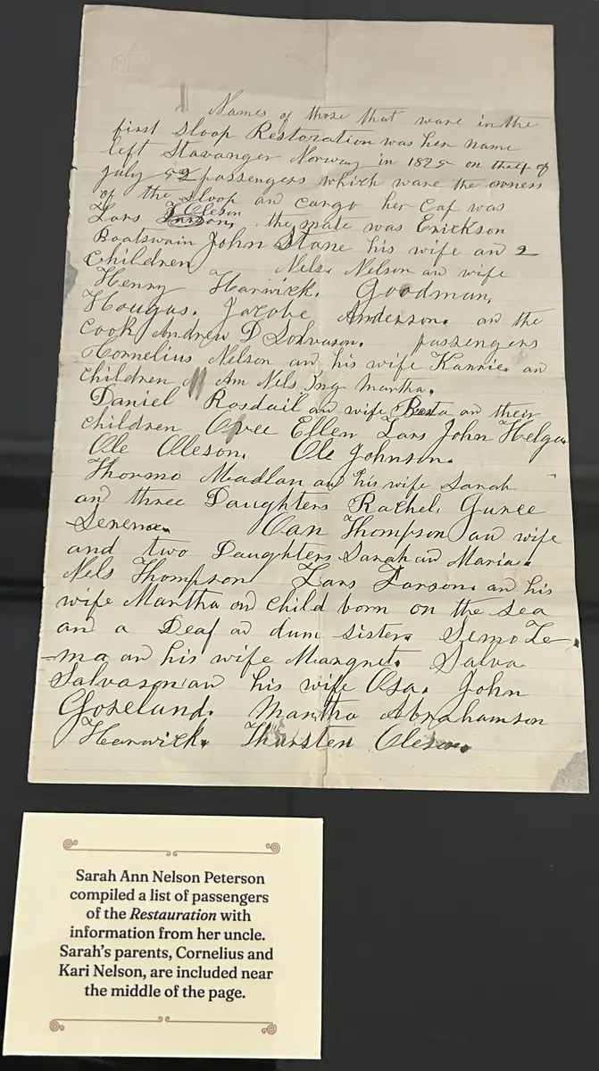 Ark med håndskrevet tekst og en trykt forklaring nedenfor til venstre. Sort bakgrunn. 