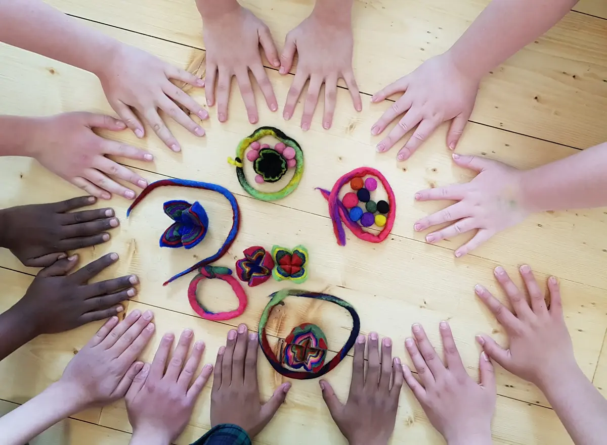 Mörka och ljusa händer i en cirkel runt slöjdade alster.