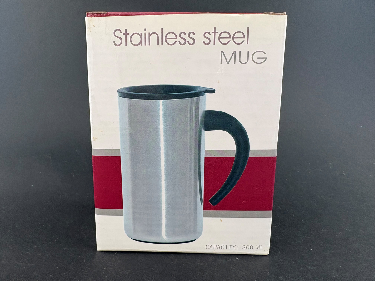 Termokrus. Original eske av kartong. Blankt metall, sort hank og lokk med drikkespalte. Posten-logo over "oss mennesker imellom".