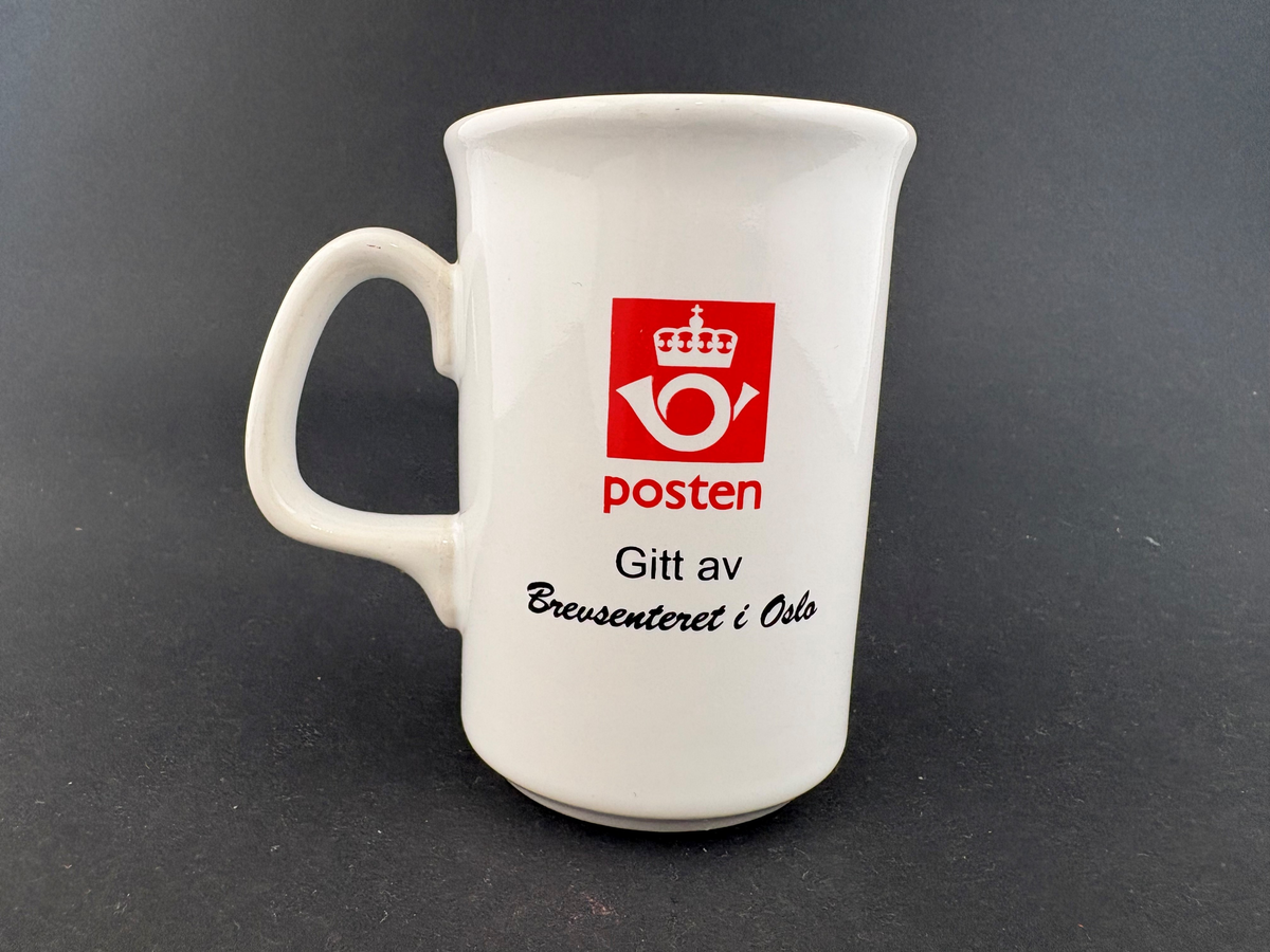 Hvitt krus med postlogo og tekst, og logo for Brevpost IL og sort tekst.