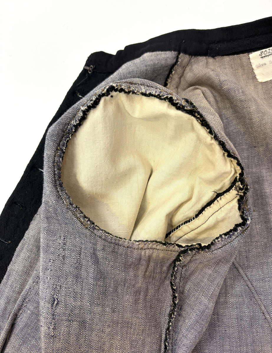 Kjoleliv i svart ull i hjemmevevd toskaft med ermer og bol i samme stoff. Livet er i dag i god stand med noen hull og ellers liten slitasje. Sydd for maskin og hånd med panelsøm og bakovertrekte skuldersømmer og sidesømmer. Rund rigning i halsen og buet fremkant. 2,5 cm bred halslinning i svart kjøpebånd i bomull, sydd på med faldesting og prikkesting med svart bomullstråd. Lukket med 8 svarte kjøpeknapper med preget blomstermønster i horn. Knapphullene er sydd for hånd med svart ulltråd og brun lintråd. Livet har et innsnitt som er 3 cm på det bredeste under bysten, sydd med maskin. Smal tosøms krokarm. Livet er helfôret med ubleket og grå bomull i fiskebensmønster i hjemmevevd toskaft og sydd på samtidig som ullstoffet ble sydd sammen med maskin og spilesøm med tykk bomullstråd for hånd. Nedkanten av livet er kantet med et 0,5 cm bredt ubleket bomullsbånd i hjemmevevd toskaft, sydd på med maskin, lagt over og festet med faldesting for hånd med brun bomullstråd. Midt på bak har livet en 5 cm lang splitt, også kantet med bomullsbåndet. Livet brukes ned i stakken og har en påsydd metallkrok bak til å hekte stakken på.