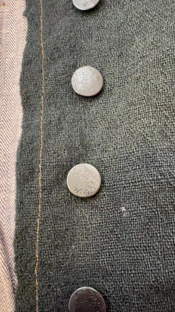 Kjoleliv i svart ull i hjemmevevd toskaft med ermer og bol i samme stoff. Livet er i dag i god stand med noen hull og ellers liten slitasje. Sydd for maskin og hånd med panelsøm og bakovertrekte skuldersømmer og sidesømmer. Rund rigning i halsen og buet fremkant. 2,5 cm bred halslinning i svart kjøpebånd i bomull, sydd på med faldesting og prikkesting med svart bomullstråd. Lukket med 8 svarte kjøpeknapper med preget blomstermønster i horn. Knapphullene er sydd for hånd med svart ulltråd og brun lintråd. Livet har et innsnitt som er 3 cm på det bredeste under bysten, sydd med maskin. Smal tosøms krokarm. Livet er helfôret med ubleket og grå bomull i fiskebensmønster i hjemmevevd toskaft og sydd på samtidig som ullstoffet ble sydd sammen med maskin og spilesøm med tykk bomullstråd for hånd. Nedkanten av livet er kantet med et 0,5 cm bredt ubleket bomullsbånd i hjemmevevd toskaft, sydd på med maskin, lagt over og festet med faldesting for hånd med brun bomullstråd. Midt på bak har livet en 5 cm lang splitt, også kantet med bomullsbåndet. Livet brukes ned i stakken og har en påsydd metallkrok bak til å hekte stakken på.