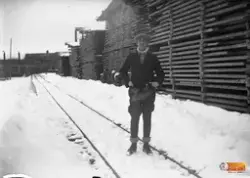 okänd man poserar framför ett virkesupplag Synpunkt tillagd: