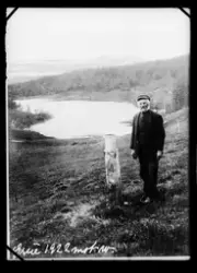 Bilde av mann ute på jorde med tjern i bakgrunnen