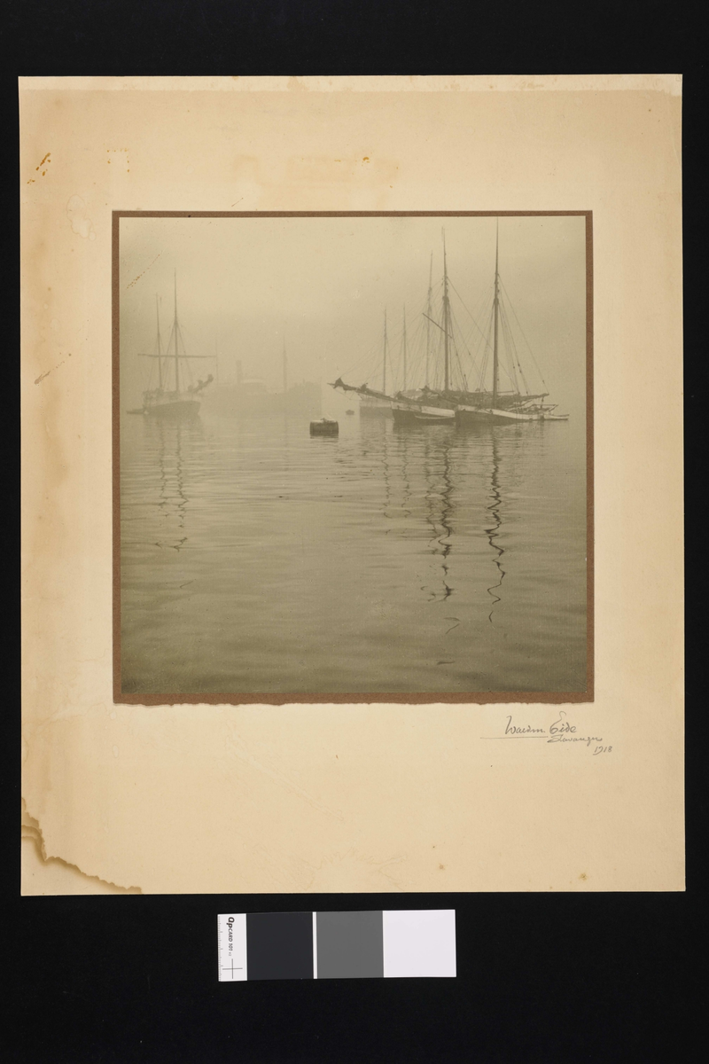 Båter i havnen med seilmaster som speiler seg i vannet.