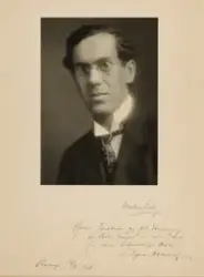 Portrett av en mann med mørkt hår og briller.