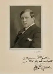 Portrett av mann med frisert hår, iført dressjakke.