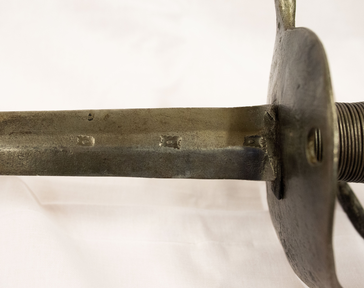 Värja, kommisvärja (ursprungligen modell 1685). 1832 ändrad till huggare för flottan. Kavelns lindning av svärtad järntråd. 