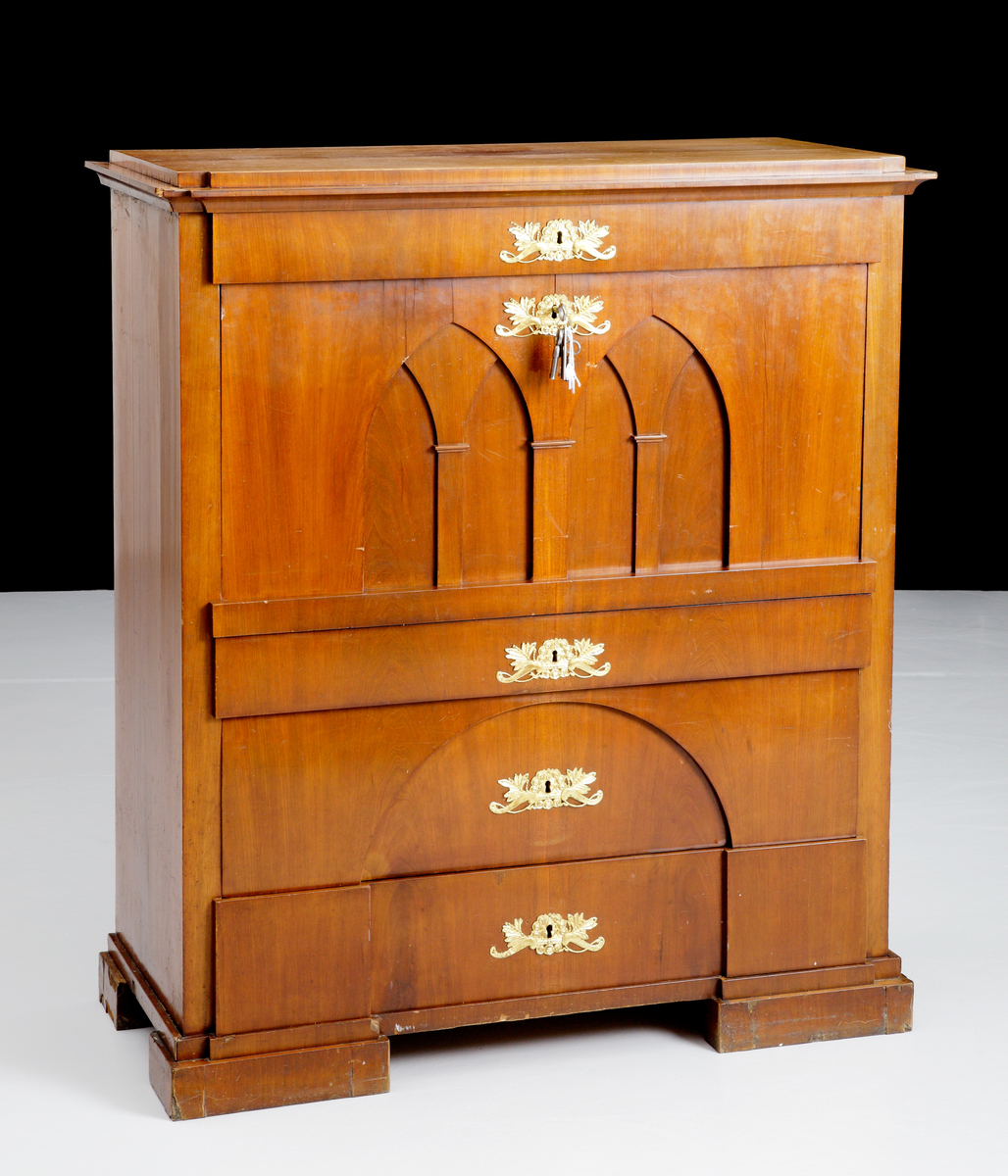 Chiffonje av mahogny. Fanerat och med intarsia på den inre inredningen. Utförd med speciell inredning med flera lönnfack. Lådorna och klaffen har förgyllda beslag. Har varit brukad för förvaring.
Inskriven i huvudkatalog 1943.