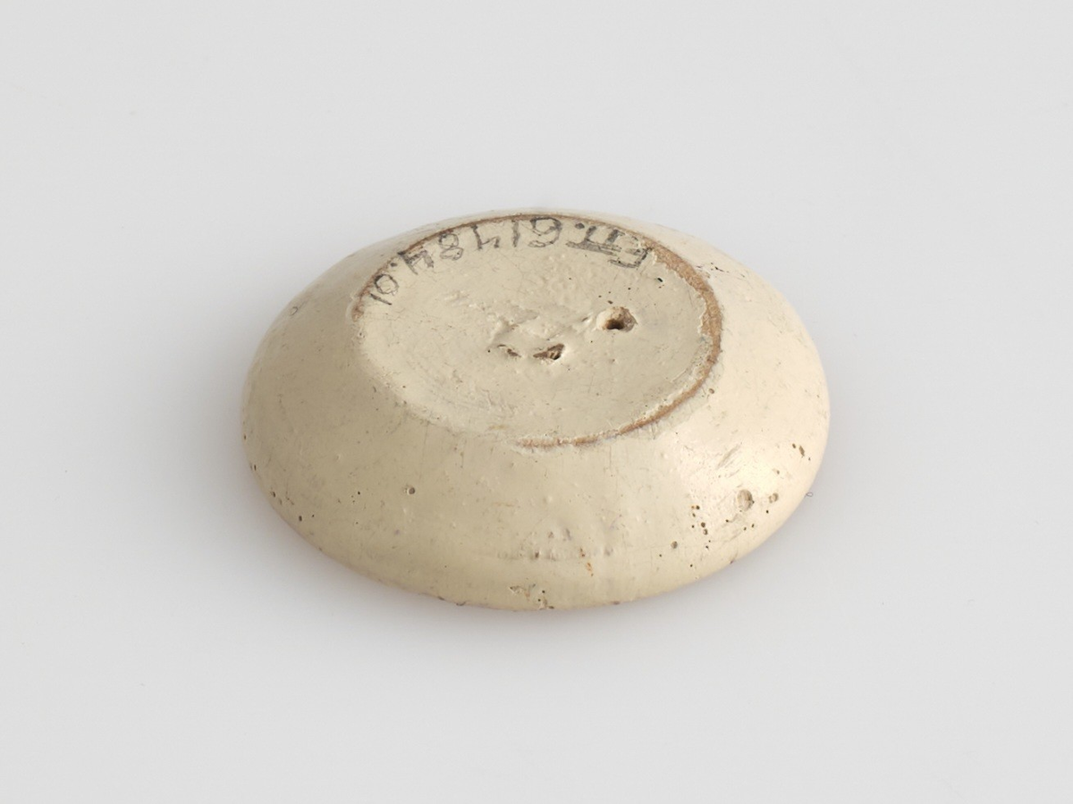 Serveringssett i miniatyr, lagd av tre.
Settet består av en tallerken, en kopp, en mugge og en krukke. Hele settet er malt i samme farger dekorert med likt mønster, utenom tallerkenen som ikke har malt mønster.
Tallerkenen har forhøyet kanter, og er malt rosa på innsiden, med hvite kanter og hvit underside.
Koppen er malt hvit på innsiden, og har en svartmalt hank. Hanken er øreformet og er festet fra kanten øverst til hvor koppen buer seg innover ved foten. Utsiden av koppen er malt rosa, og dekorert med blåe streker som danner trekanter med ujevne linjer rundt koppen. På toppen av trekantene er det malt en rød sirkel.
Krukken er sylinder-formet og snevres inn i mot toppen, før den vies skrått utover rundt åpningen. Krukken er malt hvit på innsiden, og rosa på utsiden, utsiden er også dekorert med samme mønster som koppen. Kanten rundt krukkens åpning er delvis brukket av.
Muggen er sylindret-formet, og snevres inn mot toppen, hvor kanten rundt åpningen forhøyes mot helletuten på den ene siden. På motsatt side av helletuten er det festet en svart-malt hank. Oversiden av hanken er rett, og bues ned mot bunnen av muggen. Muggen er malt og dekorert likt som koppen.