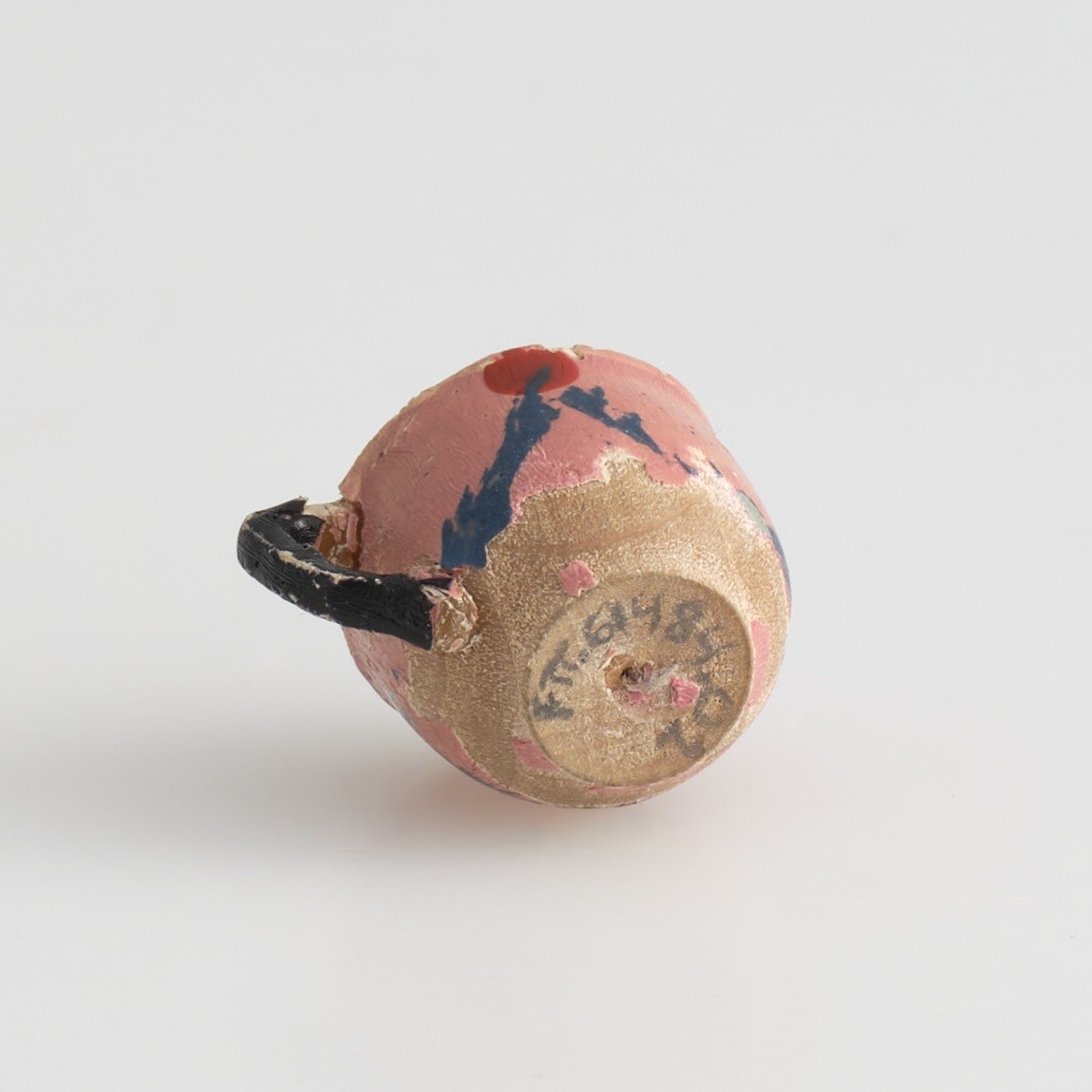 Serveringssett i miniatyr, lagd av tre.
Settet består av en tallerken, en kopp, en mugge og en krukke. Hele settet er malt i samme farger dekorert med likt mønster, utenom tallerkenen som ikke har malt mønster.
Tallerkenen har forhøyet kanter, og er malt rosa på innsiden, med hvite kanter og hvit underside.
Koppen er malt hvit på innsiden, og har en svartmalt hank. Hanken er øreformet og er festet fra kanten øverst til hvor koppen buer seg innover ved foten. Utsiden av koppen er malt rosa, og dekorert med blåe streker som danner trekanter med ujevne linjer rundt koppen. På toppen av trekantene er det malt en rød sirkel.
Krukken er sylinder-formet og snevres inn i mot toppen, før den vies skrått utover rundt åpningen. Krukken er malt hvit på innsiden, og rosa på utsiden, utsiden er også dekorert med samme mønster som koppen. Kanten rundt krukkens åpning er delvis brukket av.
Muggen er sylindret-formet, og snevres inn mot toppen, hvor kanten rundt åpningen forhøyes mot helletuten på den ene siden. På motsatt side av helletuten er det festet en svart-malt hank. Oversiden av hanken er rett, og bues ned mot bunnen av muggen. Muggen er malt og dekorert likt som koppen.