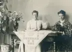 Fru Elisabeth Bergstedt, dottern Margareta och fru Mathilda Rehnström sitter på en dyschatell med ett spelbord framför sig.
På bordet syns ett syskrin med sammetsklädsel.