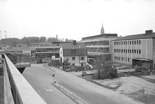 Fotografi som är taget från den då nya gjutna motorbron Mölndals bro.


Bredvid skylten där det står Domus på, så finns en vit banderoll uppsatt där det står "öppnar här 11/11". Eftersom Mölndalsbro invigs 1976-11-11, så borde fotografiet vara taget tidigare under år 1976.
Dessutom finns skyltar med namnen Hennes och Mauritz, längre ned på fasaden till byggnaden till höger. 

I bakgrunden skymtar Fässbergs kyrktorn och tittar man nog så ser man även en fabriksskorsten skymta fram till vänster i bakgrunden.