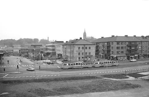 Fotografi som är taget från den då nya gjutna motorbron Mölndals bro.


Bredvid skylten där det står Domus på, så finns en vit banderoll uppsatt där det står "öppnar här 11/11". Eftersom Mölndals bro invigs 1976-11-11, så borde fotografiet vara taget tidigare under år 1976.

I bakgrunden skymtar Fässbergs kyrktorn och tittar man noga så ser man även en fabriksskorsten skymta fram i bakgrunden.

Hantverkshuset med Götabanken syns i mitten av bilden och framför syns spårvagnsspåren med två ihopkopplade spårvagnar som är på väg in till ändhållplatsen Broplatsen.