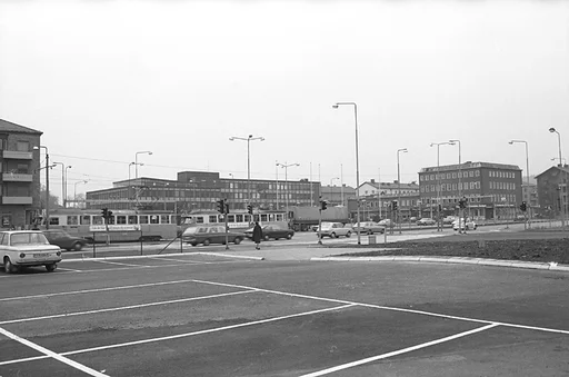 Fotografiet visar en vy som visar stadshuset och på avstånd platsen där Mölndals stadsbibliotek och Folkets hus ligger samlade.
Människor går på trottoarer och personbilar kör i riktningar både till och från Göteborg.

Mölndals Taxistation, med adressen Tempelgatan 2, syns om man tittar riktigt noga, nära belägen till vänster om stadshuset på fotografiet.