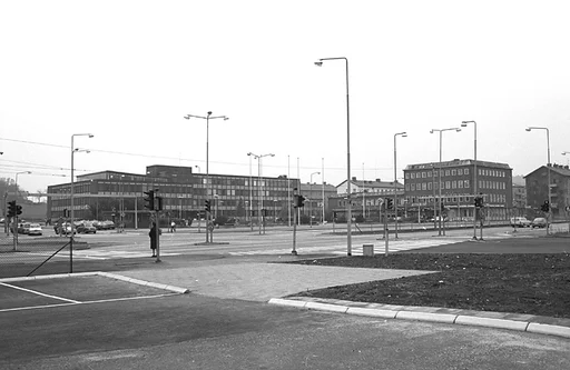 Fotografiet visar en vy som visar stadshuset och på avstånd platsen där Mölndals stadsbibliotek och Folkets hus ligger samlade.
Människor går på trottoarer och personbilar kör i riktningar både till och från Göteborg.

Mölndals Taxistation, med adressen Tempelgatan 2, syns om man tittar riktigt noga, nära belägen till vänster om stadshuset på fotografiet.