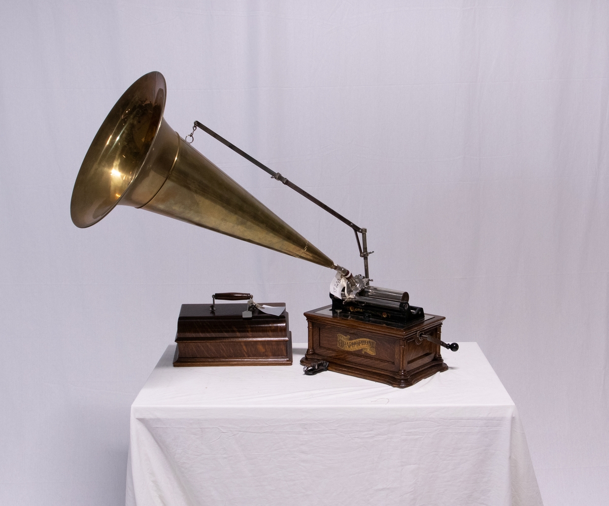 Sveivefonograf. Comlumbia Graphophone modell BF, også kalt "Peerless", nr. 7644. Fonografen er laget for av- og innspilling av 2- og 3 minutters sylindere. Avspillingslydhodet er en "Lyric" nr. 55735. Innspillingslydhodet er uten nr. og navn. Motoren er sveivetrukket med 4 fjærer.

Kassen er i brun eik med buet avtagbart lokk. Kassen er dekorert med utskjærte søyler i hjørnen. På baksiden av kassen er det montert et opphengsstativ til et stort messinghorn.