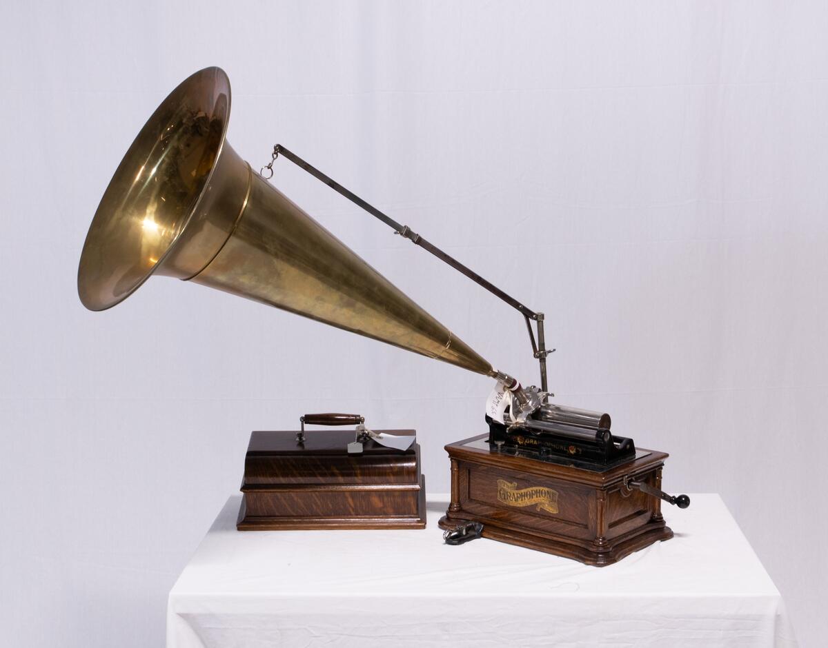 Sveivefonograf. Comlumbia Graphophone modell BF, også kalt "Peerless", nr. 7644. Fonografen er laget for av- og innspilling av 2- og 3 minutters sylindere. Avspillingslydhodet er en "Lyric" nr. 55735. Innspillingslydhodet er uten nr. og navn. Motoren er sveivetrukket med 4 fjærer.

Kassen er i brun eik med buet avtagbart lokk. Kassen er dekorert med utskjærte søyler i hjørnen. På baksiden av kassen er det montert et opphengsstativ til et stort messinghorn.