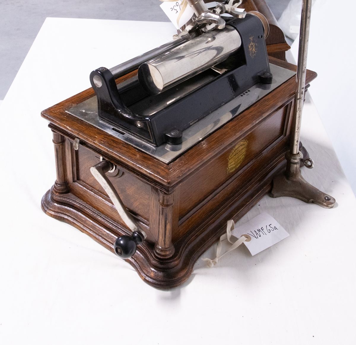 Sveivefonograf. Comlumbia Graphophone modell BF, også kalt "Peerless", nr. 7644. Fonografen er laget for av- og innspilling av 2- og 3 minutters sylindere. Avspillingslydhodet er en "Lyric" nr. 55735. Innspillingslydhodet er uten nr. og navn. Motoren er sveivetrukket med 4 fjærer.

Kassen er i brun eik med buet avtagbart lokk. Kassen er dekorert med utskjærte søyler i hjørnen. På baksiden av kassen er det montert et opphengsstativ til et stort messinghorn.