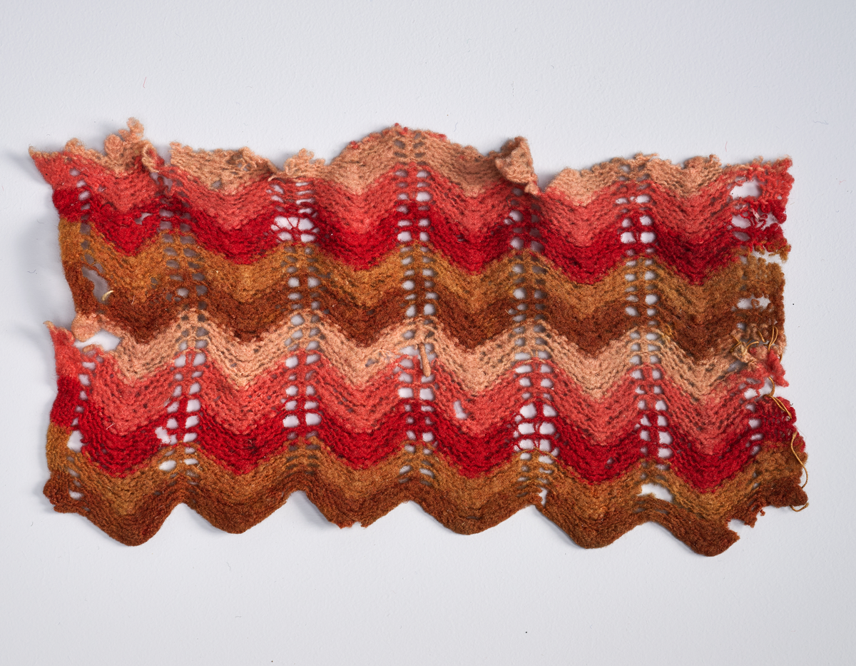 Ulike strikkete stoffrester i ulike farger og mønster. Et stoff er et brodert stoltrekk med blomstermønster. Funnet i en kasse tilhørende Hans Nissengården.