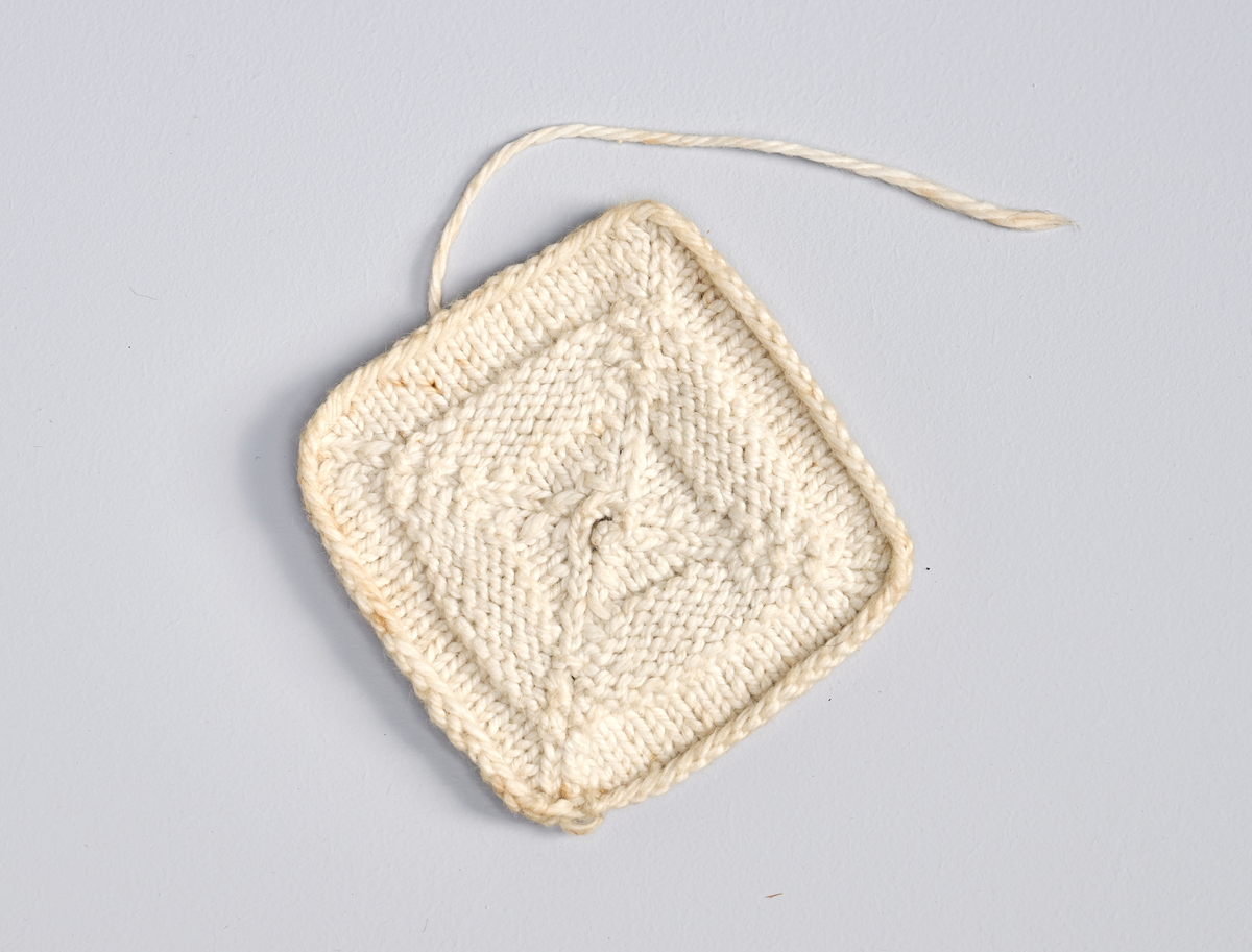 Ulike strikkete stoffrester i ulike farger og mønster. Et stoff er et brodert stoltrekk med blomstermønster. Funnet i en kasse tilhørende Hans Nissengården.