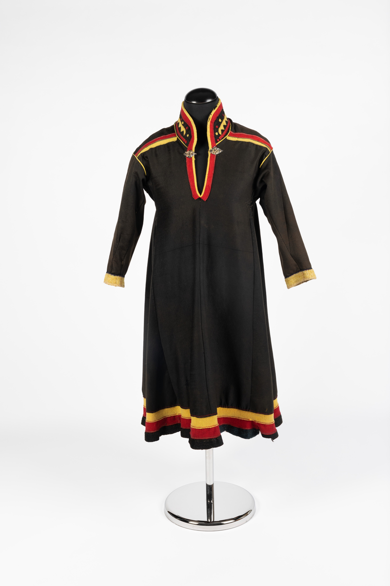 Svart kofte av klede med dekor av gult, rødt og beige klede.