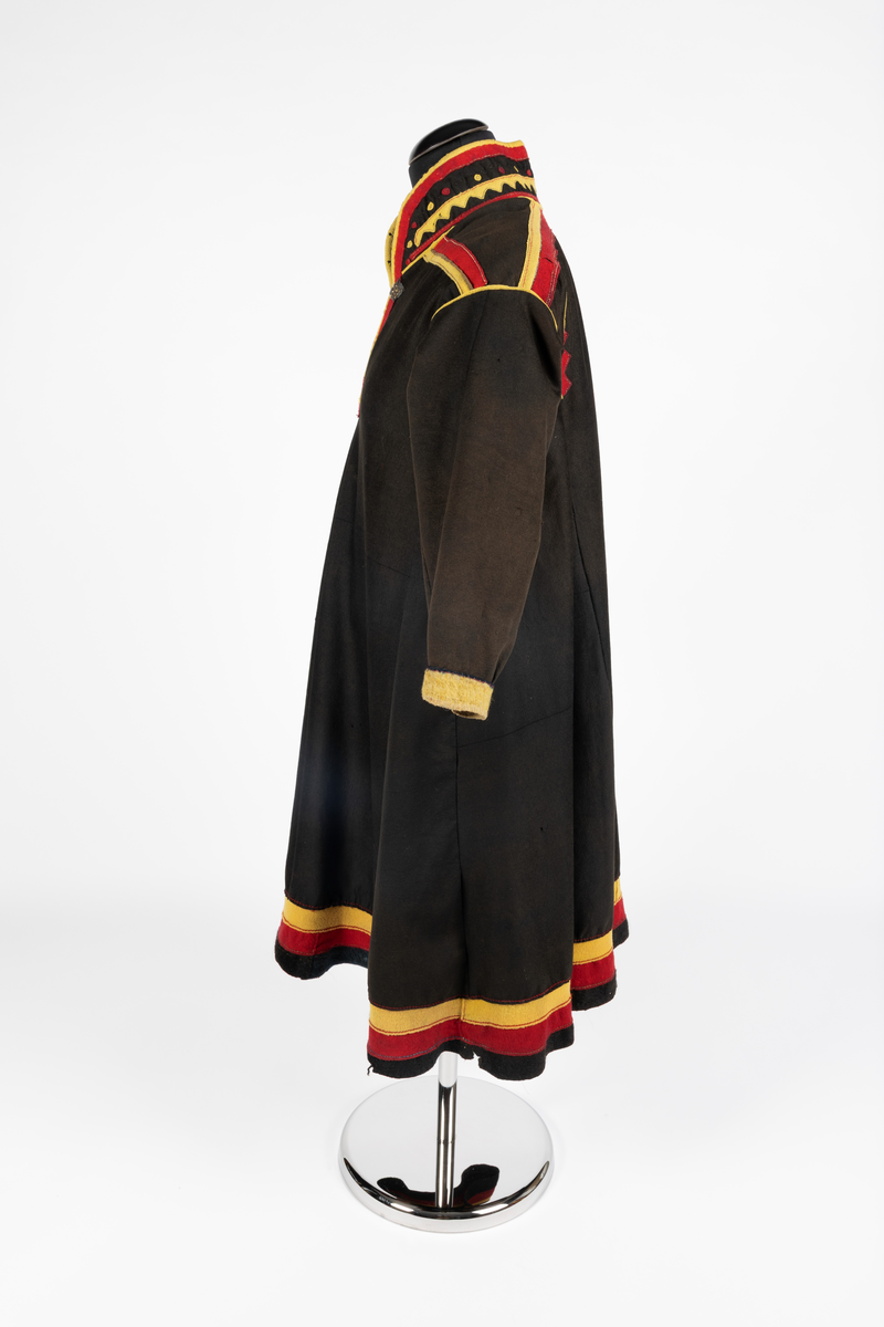 Svart kofte av klede med dekor av gult, rødt og beige klede.