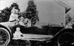 Fem barn leker i en bil. Det minste barnet sitter på stigbre