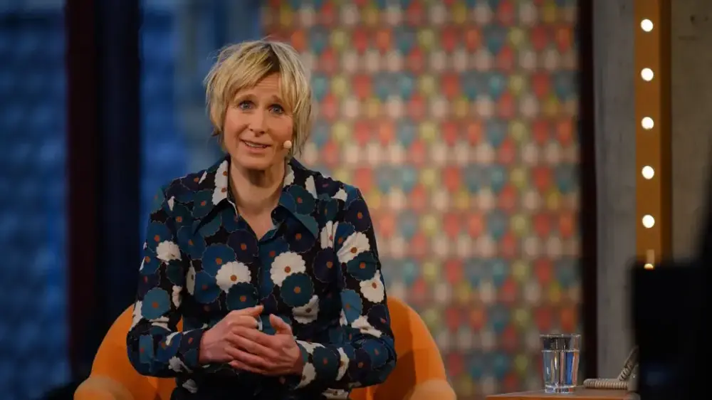 Linda Eide på scena i Grieghallen med ein blå og kvit-blomstrete bluse