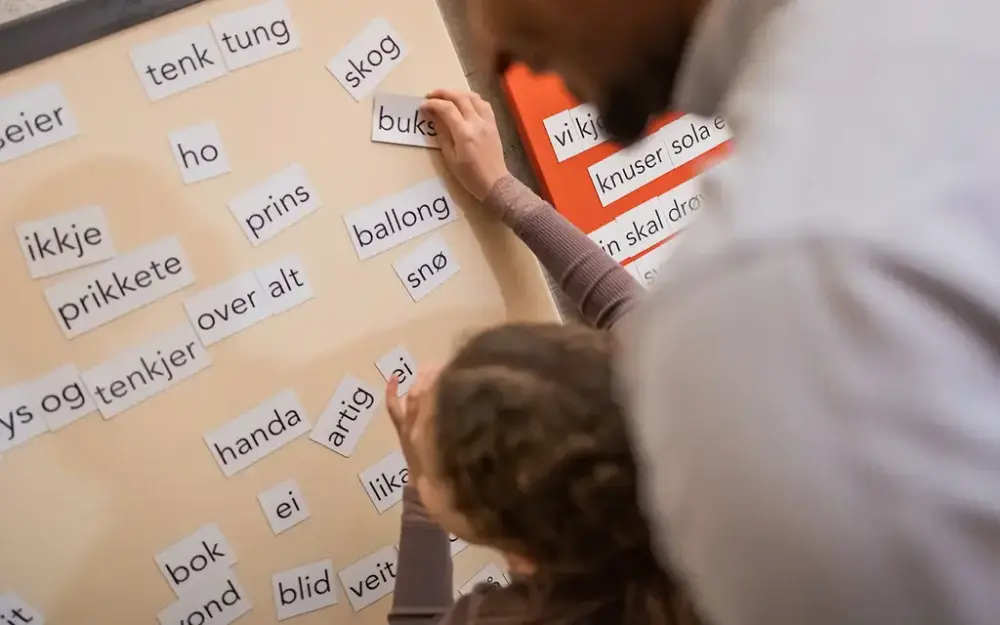Bilete av ei jente som leikar seg med ord på ei magnettavle på Lurivarrommet i Aasentunet.