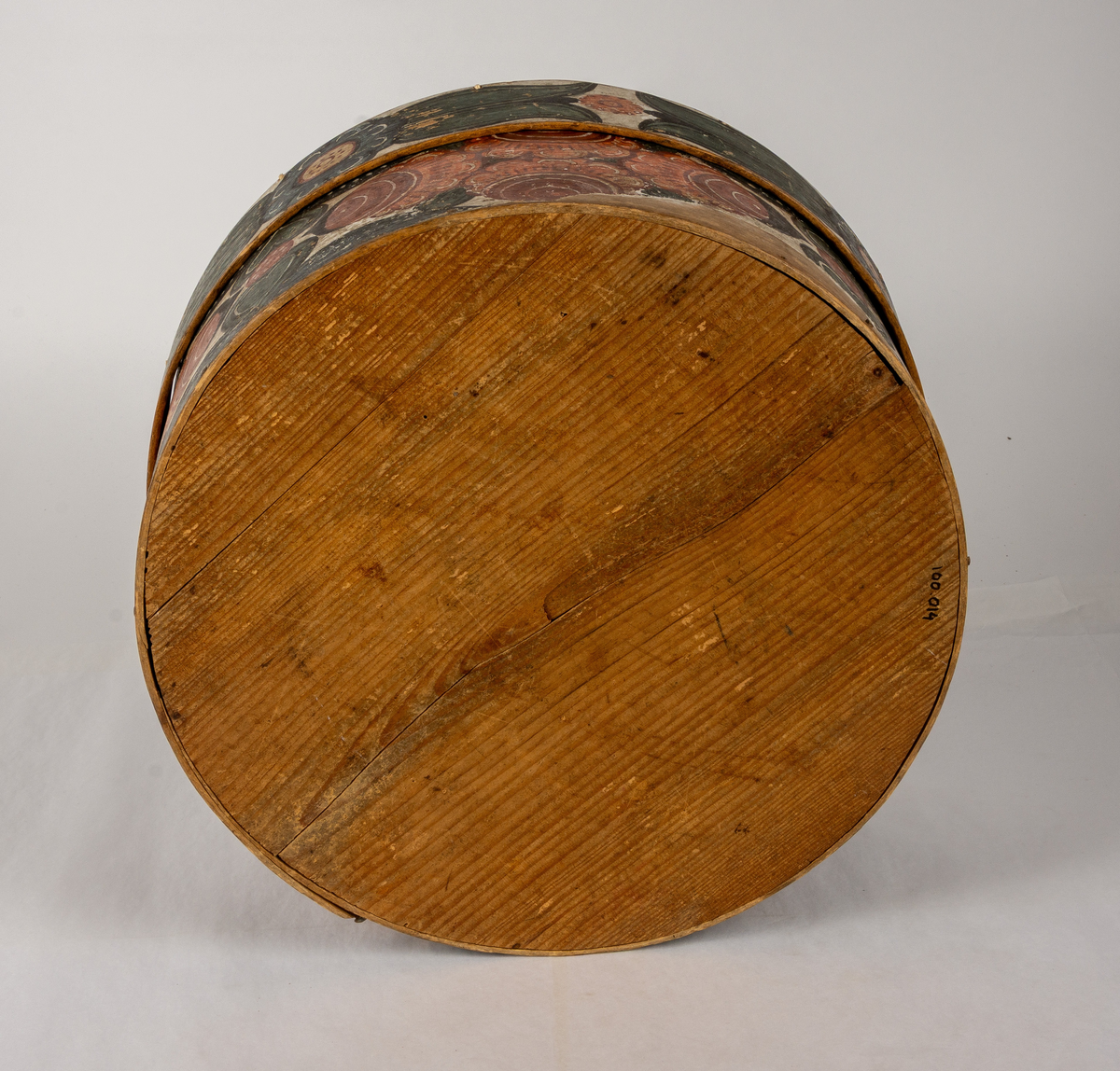 Cylindrisk, svept ask av björk, botten och lock av furu. Målat rosmotiv i rött och blått. Initialerna KJD samt årtalet 1806 på locket.