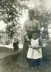 Fru Elisabeth Bergstedt med dottern Margareta i en trädgård. Till vänster syns ännu ett barn, i kolt.
