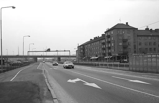 I bakgrunden skymtar Mölndals bro.

Människor går på trottoarer och personbilar kör i riktningar både till och från Göteborg.

Till höger skymtar ett vindskydd som hör till den numera borttagna spårvagnshållplatsen Tempelgatan, i riktning mot Göteborg.