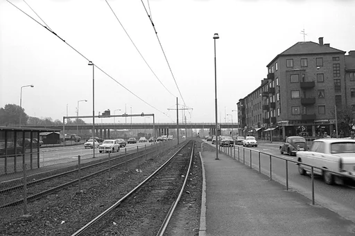 Fotografiet är taget på den numera borttagna spårvagnshållplatsen Tempelgatan, i närheten av stadshuset. Tiden torde vara någon gång i början av 1970-talet.

I bakgrunden skymtar Mölndals bro.

Mäniskor går över övergångsstället vid Tempelgatan 2, höger i bild, medan biltrafiken kör förbi, både in till Göteborg och till Mölndalsbro.