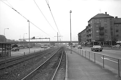 Fotografiet är taget på den numera borttagna spårvagnshållplatsen Tempelgatan, i närheten av stadshuset. Tiden torde vara någon gång i början av 1970-talet.

I bakgrunden skymtar Mölndals bro.

Vi ser hörnet på Tempelgatan 2, höger i bild, medan biltrafiken kör förbi, både in till Göteborg och till Mölndalsbro.