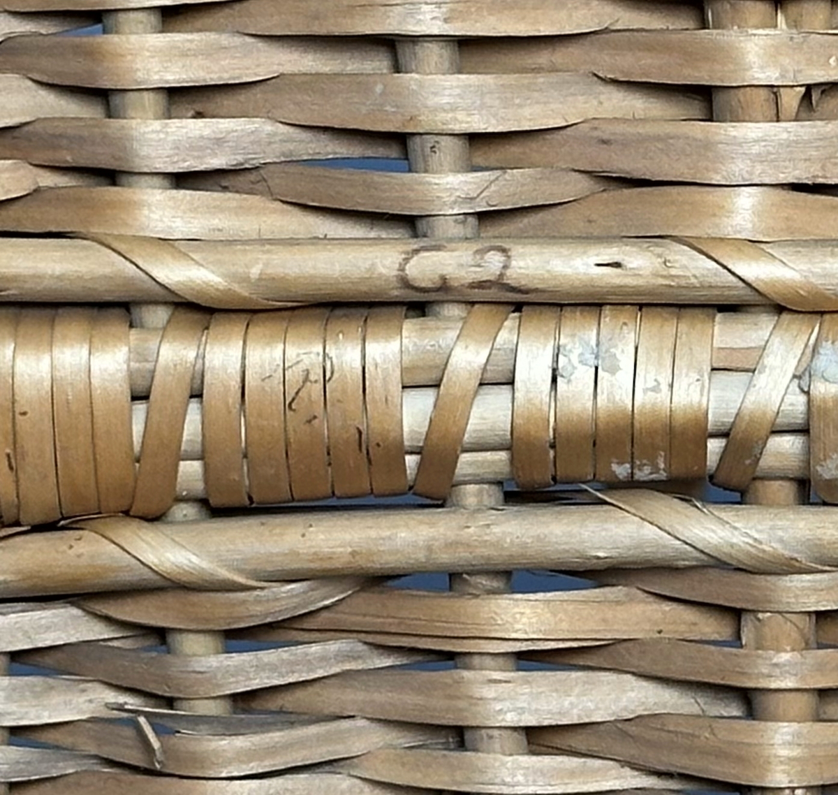 Rektangulär korg med rundade hörn, flätad i tuskaft av pil på böjda vidjor från botten till stående varp. Har ett lindat handtag mitt över av delad pil.