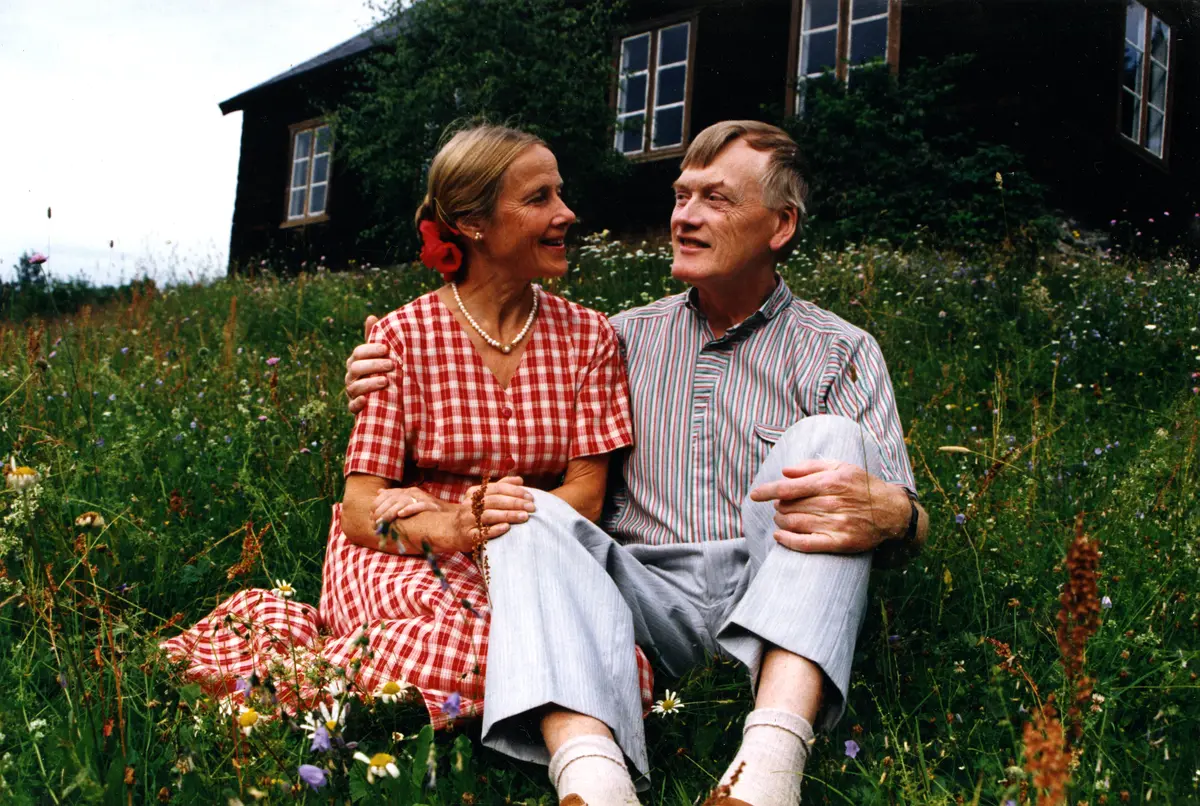 Dame og mann sittande i blomstereng