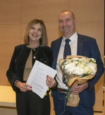 Riksarkivar Inga Bolstad og administrerende direktør i Anno, Sven Inge Sunde, smiler til fotografen med den undertegnede overtakelseskontrakten og en blosterbukett i hendene.