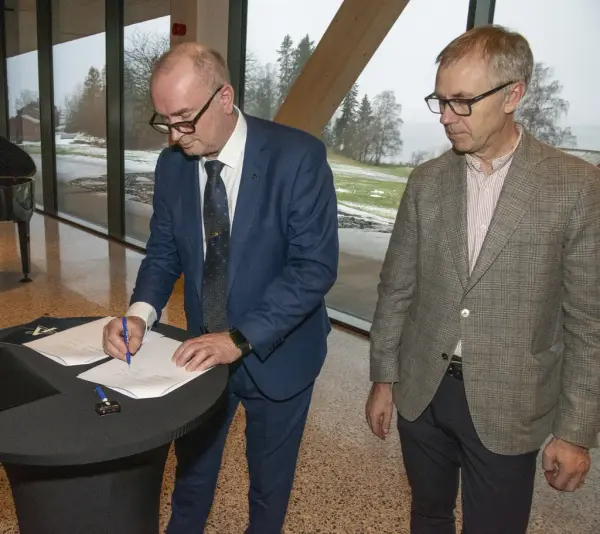 Adm.dir. i Anno, Sven Inge Sunde, signerer overtakelsespapirene for Anno Domkirkeodden historiesenter, mens Øystein Nordal fra hovedentreprenør Martin M. Bakken står ved siden av.